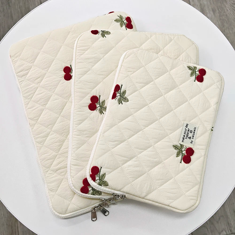 Une pochette ordinateur matelassée, brodée de cerises rouges